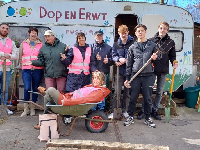 Groep mensen voor een caravan aan het werk.
