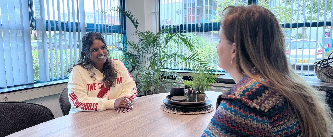 Twee vrouwen voeren een gesprek aan tafel.